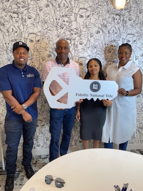 Marlon Wilson with clients holding a large key during a title office closing photo.