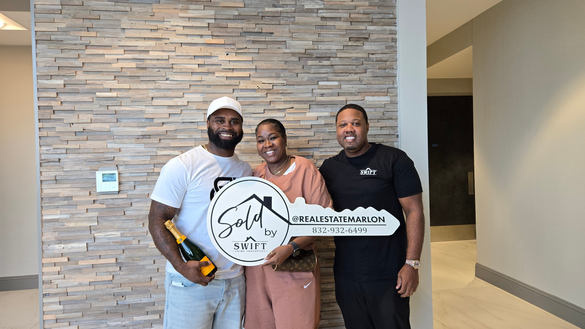 Marlon Wilson with two happy clients holding a sold key sign after a successful closing.